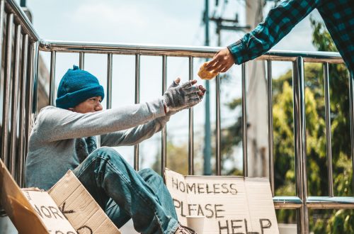 The man sitting begging on an overpass with messages homeless people please help and work well with food.